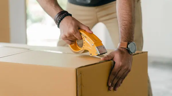 Man sealing a cardboard box with packing tape