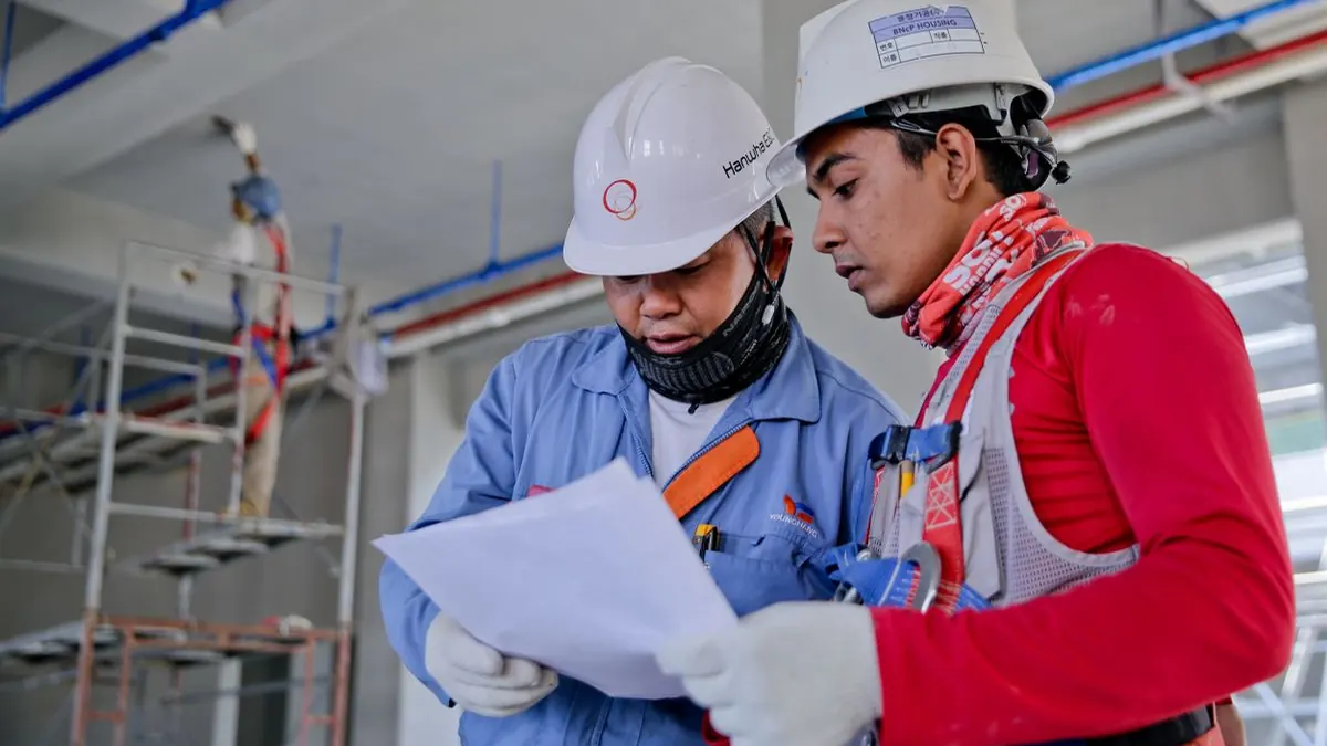 Two engineers in hard hats reviewing plans on a construction site