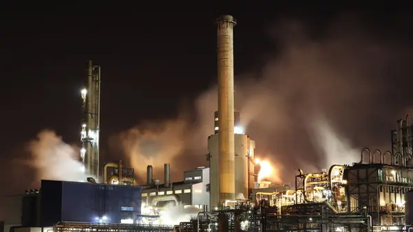 Oil refinery with chimneys and lights at night