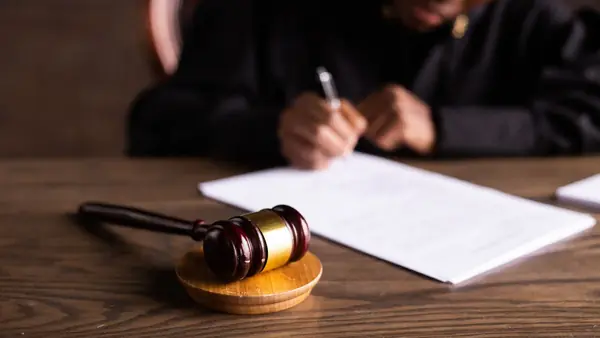 شخص يوقّع مستندًا بجانب مطرقة قاضٍ